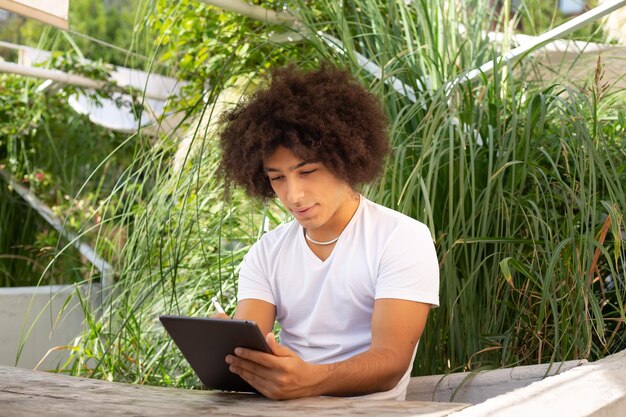 A student is using a tablet with an interactive learning app in a comfortable outdoor setting. The app displays a colorful simulation, highlighting the integration of technology and personalized learning experiences.